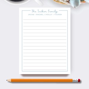 May include: A white notepad with a light blue border and the text "The Tucker Family" at the top. The names Jacob, Rachel, Molly, and Tucker are listed below. An orange pencil with a pink eraser rests at the bottom.