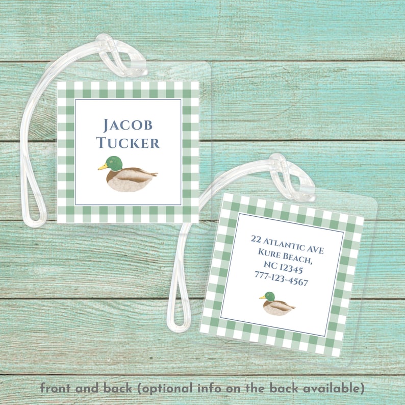 May include: A green and white gingham luggage tag with a duck illustration and the text "JACOB TUCKER". The back of the tag has the text "22 ATLANTIC AVE KURE BEACH, NC 12345 777-123-4567".