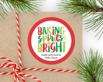 May include: A round sticker with a red border on a brown paper package tied with red and white twine. The sticker features the text "BAKING SPIRITS BRIGHT" in red and green, a small yellow star, and the text "made with love by Holly Claus".