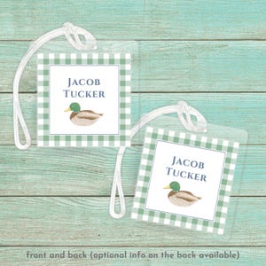 May include: Green and white gingham luggage tag with a blue duck illustration and the name "Jacob Tucker" printed in blue text.