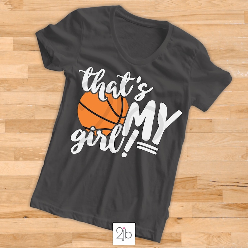 May include: A dark grey t-shirt with a white graphic that says "that's my girl!" with a basketball graphic.