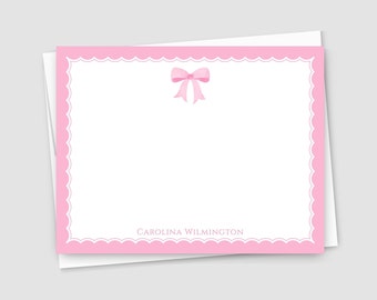 May include: Pink stationery card with a scalloped border and a pink bow in the center. The card has the text "CAROLINA WILMINGTON" at the bottom.