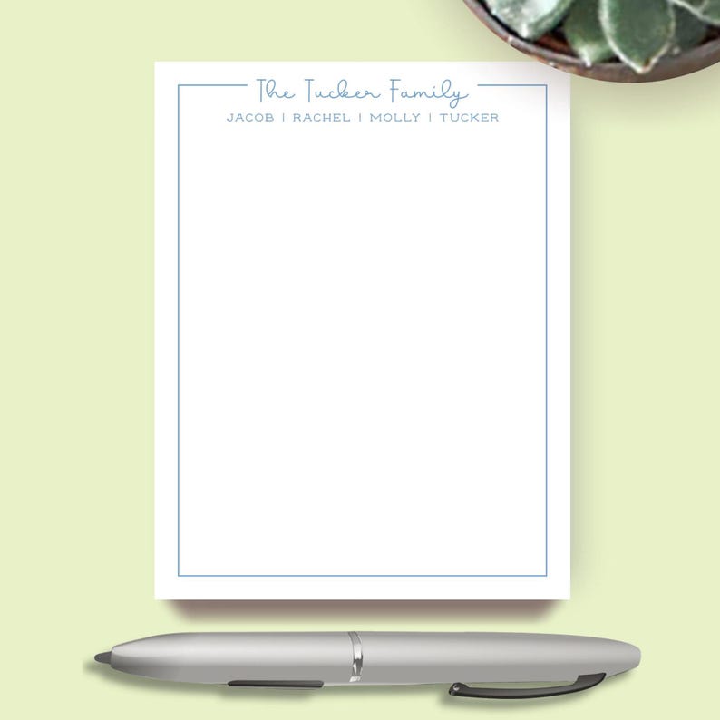 May include: A white notepad with a light blue border and the text "The Tucker Family" at the top. The names Jacob, Rachel, Molly, and Tucker are listed below. A silver pen rests at the bottom.
