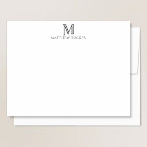 May include: White stationery set with a black envelope. The stationery has a black letter "M" with a border and the text "MATTHEW TUCKER" printed below.