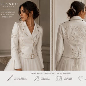 Könnte beinhalten: Cremefarbene Lederjacke im Motorradstil. Sie hat einen Reißverschluss, einen Gürtel und Stickereien. Auf dem Rücken der Jacke steht "Mrs. Smith" und "EST. 2026". Die Jacke ist Teil einer Brautkollektion.