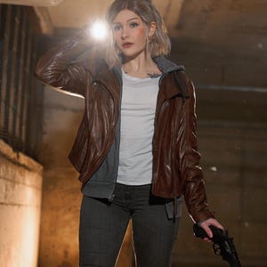 May include: A brown leather jacket with a white shirt and gray hoodie underneath. The person is holding a black handgun and a flashlight. They are wearing gray jeans. The background is a dimly lit, industrial-looking space.