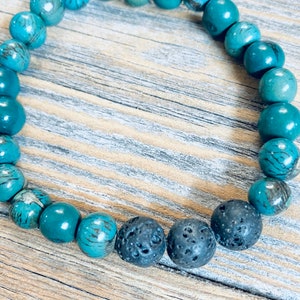 May include: A turquoise and black beaded bracelet with lava rock beads. The bracelet is made of natural stones and is designed to be worn on the wrist.