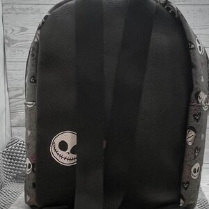 Puede incluir: Mochila negra con dise&ntilde;o de Jack Skellington. Tiene correas negras ajustables y un asa superior. El cuerpo principal es negro con un parche blanco con la cara de Jack Skellington. Los laterales tienen un patr&oacute;n repetido de Jack Skellington y otros personajes.