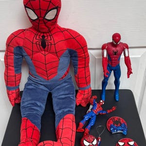 Puede incluir: Una colecci&oacute;n de juguetes y peluches con tem&aacute;tica de Spider-Man. La imagen presenta un gran mu&ntilde;eco de peluche de Spider-Man, una figura de acci&oacute;n de pl&aacute;stico y varios objetos decorativos m&aacute;s peque&ntilde;os, todos en la combinaci&oacute;n de colores rojo y azul caracter&iacute;stica del personaje.