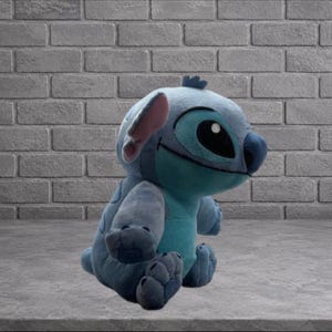 Puede incluir: Un peluche del personaje Stitch de la pel&iacute;cula de Disney Lilo & Stitch. El juguete es principalmente azul con una panza turquesa, ojos grandes negros y orejas internas rosas. Est&aacute; sentado sobre una superficie gris frente a una pared de ladrillos.