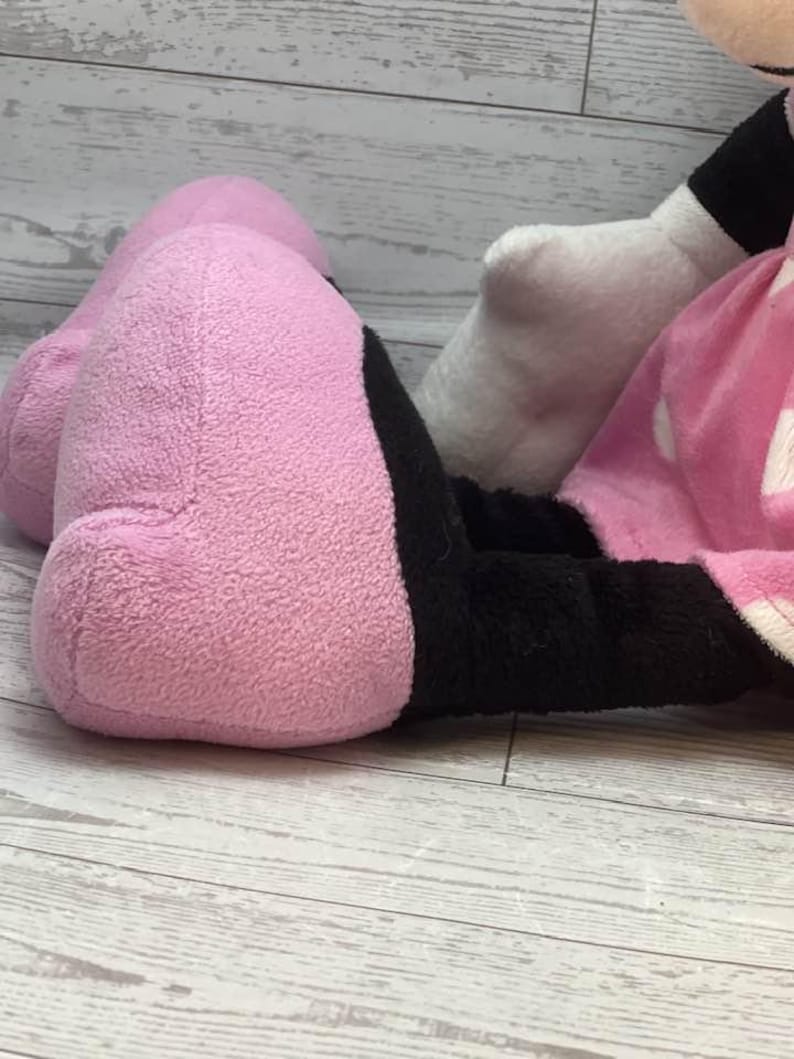 Pode incluir: Um brinquedo de pel&uacute;cia com um p&eacute; rosa e um p&eacute; preto. O p&eacute; rosa &eacute; grande e arredondado, com uma superf&iacute;cie macia e texturizada. O p&eacute; preto est&aacute; adjacente ao p&eacute; rosa. O fundo &eacute; uma superf&iacute;cie de madeira clara.