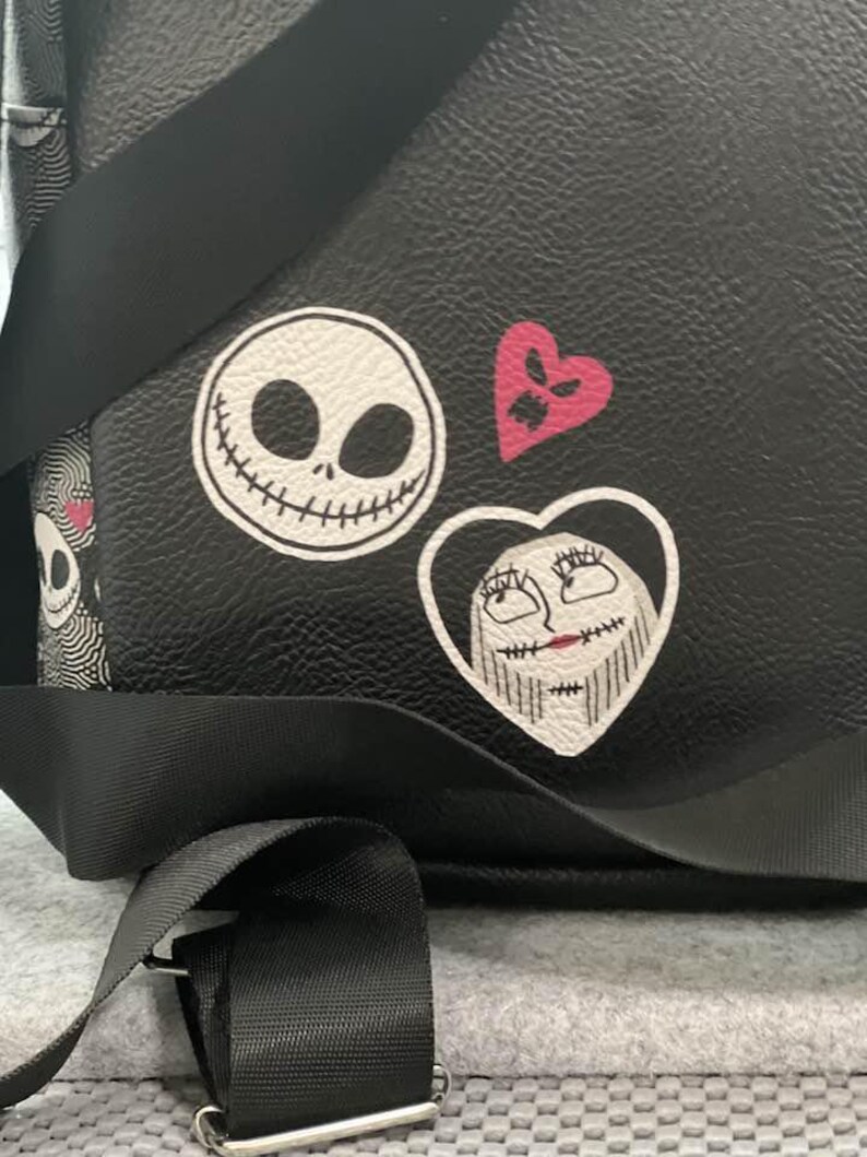 Puede incluir: Mochila negra con parches del rostro de Jack Skellington, el rostro de Sally en un coraz&oacute;n y un coraz&oacute;n rosa. La bolsa tiene correas negras y una hebilla plateada. El dise&ntilde;o es de la pel&iacute;cula "Pesadilla antes de Navidad".