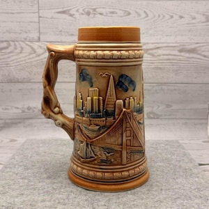 May include: A set of three ceramic mugs with a speckled, matte finish. The mugs are in shades of cream, light gray, and dark gray. Each mug has a simple, minimalist design, perfect for coffee or tea.