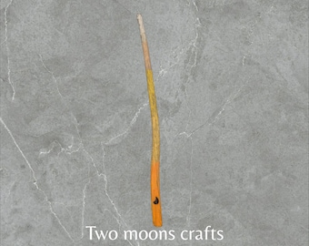 Puede incluir: Una varita de madera larga y delgada con una punta marrón oscura y un degradado amarillo y naranja. La varita está sobre un fondo gris con el texto "Two moons crafts Wands".