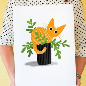 May include: A bright orange cat with black stripes sits in a black pot with green leafy plants. The cat is looking to the left of the image.