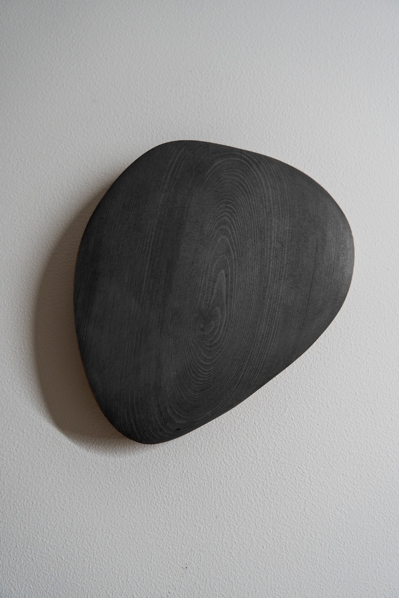 K&ouml;nnte beinhalten: Ein schwarzes Holztablett mit einer einzigartigen, organischen Form. Das Tablett ist aus dunklem Holz mit einer glatten, polierten Oberfl&auml;che.