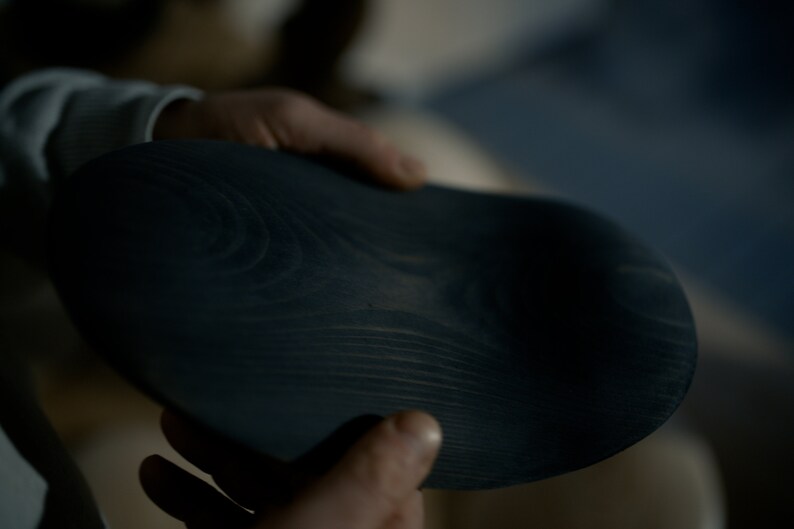 K&ouml;nnte beinhalten: Eine dunkelblaue Holzschale mit einer glatten, abgerundeten Oberfl&auml;che und sichtbarer Holzmaserung.