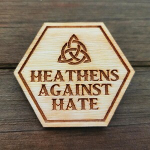 May include: A hexagonal wooden sign with a Celtic knot design and the text "Heathens Against Hate".