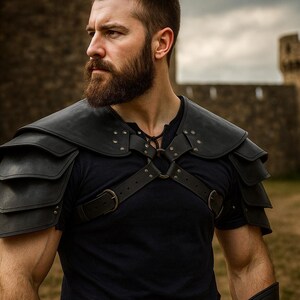 May include: Black leather shoulder armor with layered plates, secured by straps and buckles, worn over a black shirt. The armor has a medieval aesthetic. A castle is in the background.