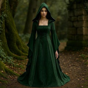 May include: A woman in a dark green hooded dress stands on a forest path. The dress has long, flared sleeves and a square neckline. The background features large trees and a stone wall, creating a mystical atmosphere.