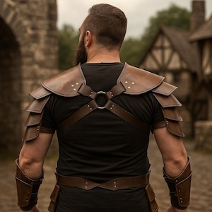 May include: Brown leather armor set, including shoulder pauldrons, arm bracers, and a chest harness with a metal ring. The armor is worn over a black shirt. The scene is set outdoors with a stone archway and buildings in the background.
