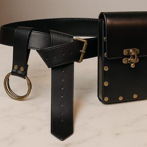 Puede incluir: Cintur&oacute;n de cuero negro con una funda a juego. El cintur&oacute;n presenta una hebilla dorada y dos anillos dorados. La funda tiene un cierre decorativo y tachuelas doradas. El cintur&oacute;n est&aacute; dise&ntilde;ado para usarse alrededor de la cintura.