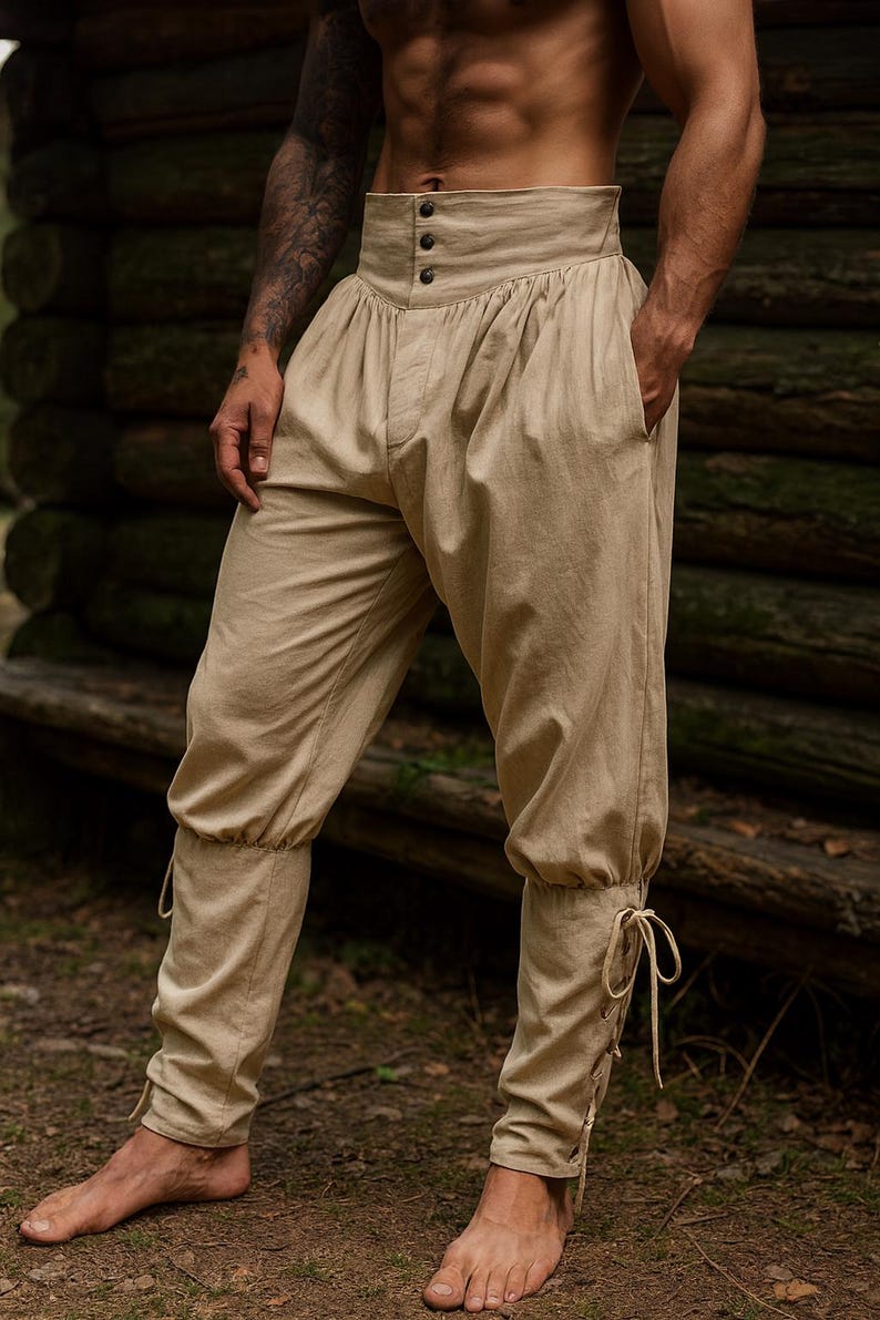 K&ouml;nnte beinhalten: Beige Hose mit hohem Bund, Knopfleiste und gerafften Details. Die Hose hat Taschen und Bindeb&auml;nder an den Kn&ouml;cheln. Der Stoff scheint eine leichte Leinen- oder Baumwollmischung zu sein. Geeignet f&uuml;r historische Nachstellungen oder Kost&uuml;mveranstaltungen.
