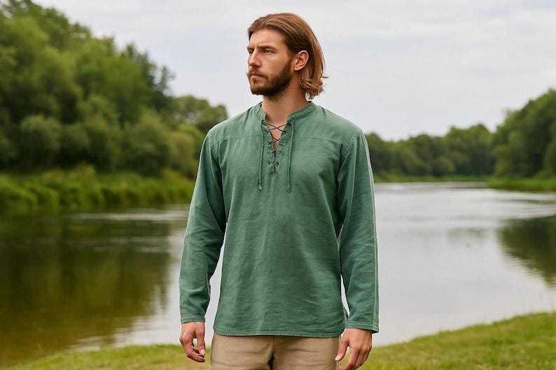 K&ouml;nnte beinhalten: Ein lang&auml;rmeliges, gr&uuml;nes Hemd mit Schn&uuml;rhalsausschnitt. Das Hemd ist aus einem weichen, strukturierten Stoff gefertigt. Das Model steht vor einem Fluss mit B&auml;umen im Hintergrund. Das Hemd ist einfarbig.