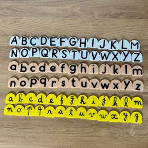 Peut inclure: Trois ensembles de lettres de l'alphabet en blanc, pêche et jaune. Les lettres sont en majuscules, minuscules et en cursive minuscule.