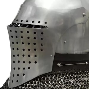 May include: A close-up of a medieval knight's helmet. The helmet is made of polished steel with a visor featuring numerous small holes for ventilation. A chainmail collar is visible at the base, providing neck protection. The design is historically accurate.