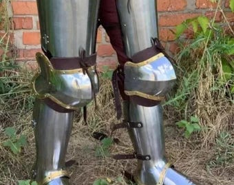 May include: Polished steel leg armor with articulated knee protection and leather straps. The armor has brass accents and is designed to protect the legs. The metal reflects the surrounding environment, creating a shiny appearance.