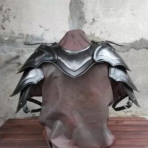 Könnte beinhalten: Schwarze Lederschulterrüstung mit einem mehrschichtigen Design. Die Rüstung besteht aus Metallplatten und hat einen dekorativen, spitzen Kragen.