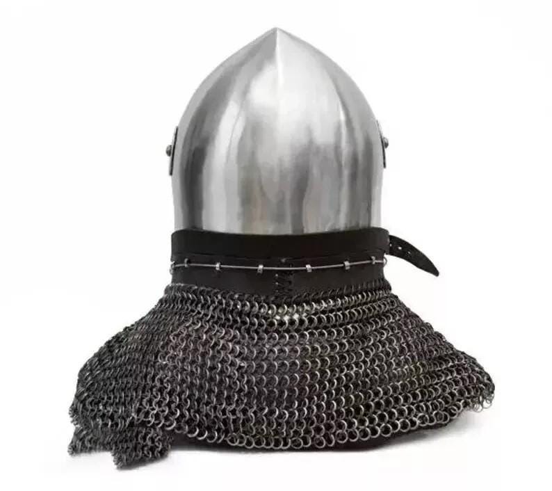 May include: A medieval helmet with a polished, silver-colored metal top and a chainmail neck guard. The helmet has a leather strap and is set against a white background. The chainmail is made of small, interlocking metal rings.