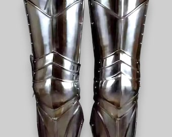 May include: A pair of silver knee armour made of metal plates. The armour is designed to protect the knees and shins during combat. The armour is made of metal plates that are riveted together. The armour is designed to be worn over clothing.