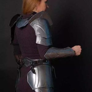 May include: A silver metal armor set for the shoulders, arms, and hips. The armor is made of metal plates and has a sleek, modern design.