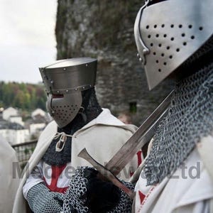 May include: Two medieval knights in full armor, including helmets, chainmail, and white capes with red crosses. One knight holds a sword. The image is set against a blurred background of a stone structure and foliage.