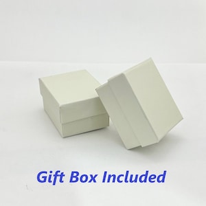 K&ouml;nnte beinhalten: Zwei wei&szlig;e Geschenkboxen, eine etwas gr&ouml;&szlig;er als die andere, sind auf einer wei&szlig;en Oberfl&auml;che zu sehen. Der Text "Gift Box Included" ist in Blau unter den Boxen gedruckt.