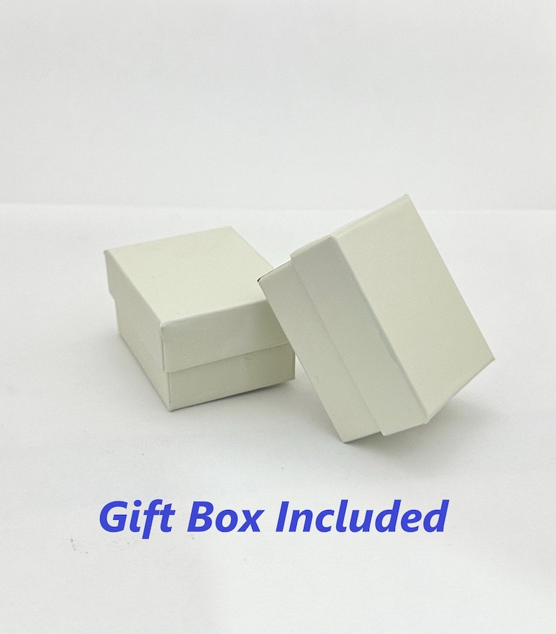 K&ouml;nnte beinhalten: Zwei wei&szlig;e Geschenkboxen, eine etwas gr&ouml;&szlig;er als die andere, sind auf einer wei&szlig;en Oberfl&auml;che zu sehen. Der Text "Gift Box Included" ist in Blau unter den Boxen gedruckt.