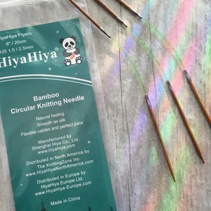 May include: A package of HiyaHiya Flyers bamboo circular knitting needles. The package includes a set of needles, 8 inches (20 cm) long, with a US 1.5 / 2.5mm size. The package has a panda logo and text that reads "Bamboo Circular Knitting Needle".