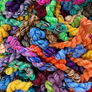 May include: A close-up of a variety of colourful yarn skeins, including shades of blue, green, purple, red, orange, and yellow.
