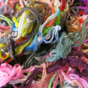 May include: A close-up of a tangled mass of colourful yarn. The yarn is in shades of pink, purple, green, yellow, blue, and red. The strands are interwoven, creating a textured effect. Ideal for knitting, crochet, and other craft projects.