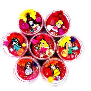 Peut inclure: Sept récipients en plastique transparent remplis de slime rouge, chacun décoré d'une figurine de princesse différente, de fleurs et de paillettes. Les princesses incluent Blanche-Neige, Aurore, Jasmine et d'autres. Les récipients sont disposés en cercle.