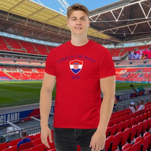 May include: Red t-shirt with a blue and white Croatian flag crest and the text "FINALS OR BUST 2026".