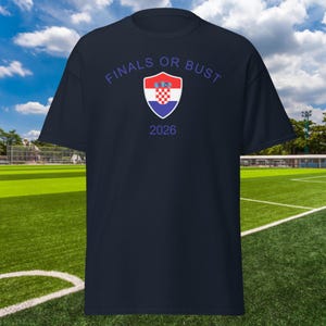 May include: A navy blue t-shirt with the text "Finals or Bust" and a Croatian coat of arms in a shield. The year 2026 is printed below the shield.