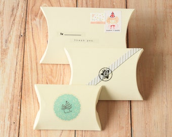 May include: Three white pillow boxes with decorative paper and stickers. The top box has the text "For ______ thank you." The middle box has a black and white striped ribbon with a black star sticker. The bottom box has a blue and white sticker with a green tree design.
