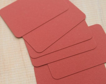 May include: A stack of six blank red index cards, arranged in a fan shape, on a light wood surface.