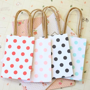 May include: Four small gift bags with polka dot patterns. The bags are white with red, pink, black, and blue polka dots. The bags have brown paper handles.