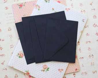 May include: A stack of navy blue envelopes rests on patterned stationery. The stationery features floral and polka dot designs in pink and white. Some stationery has the text "I love zakka".