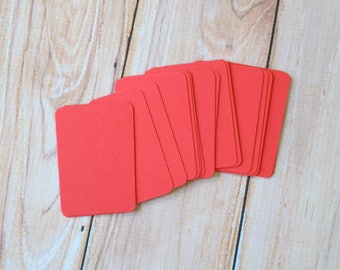 May include: A stack of bright red blank cards on a wooden surface.