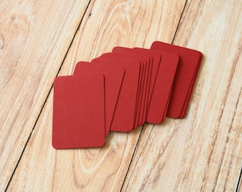 May include: A stack of red cardstock paper, arranged in a fan shape, on a wooden surface.